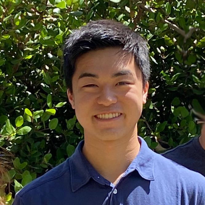 Nathan smiling while standing in front of a tree