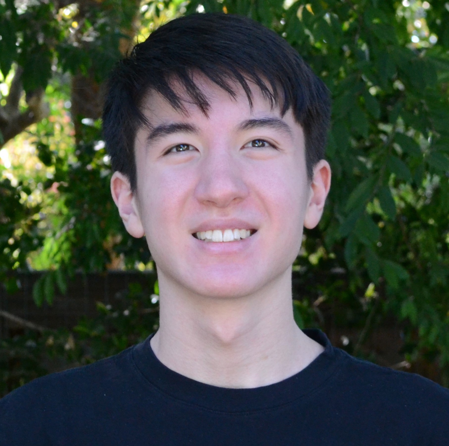 Ramsey smiling while standing in front of a tree